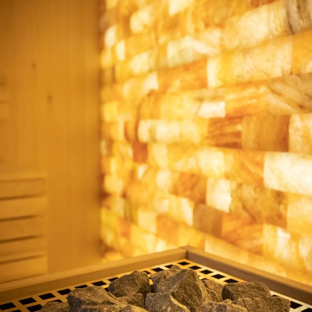 Un tas de pierres sombres est posé sur une grille devant un mur de briques éclairé par une lumière chaude