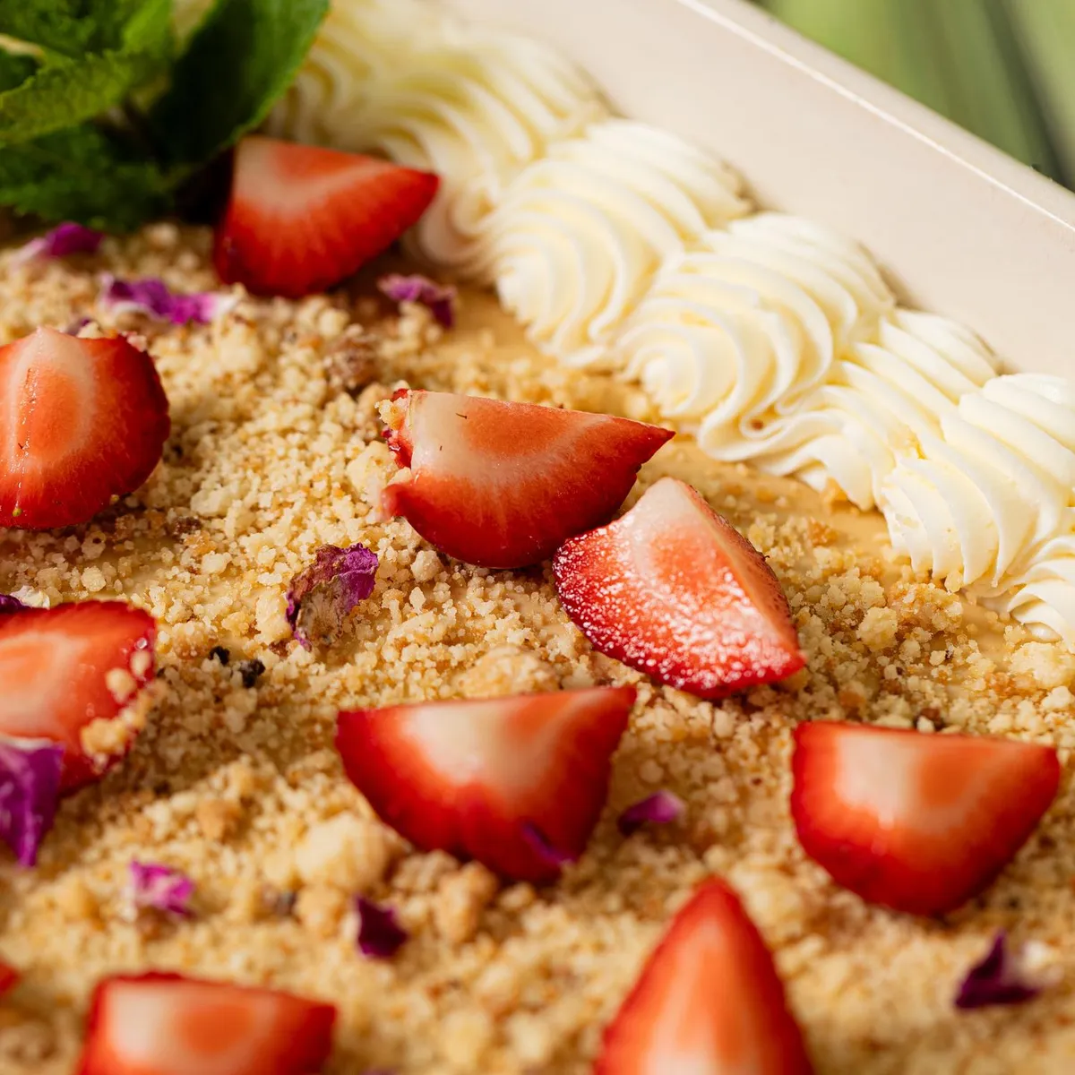 Un plat contenant des quartiers de fraises, des graines de quinoa et une garniture de crème blanche, accompagné de tiges de céleri en arrière-plan