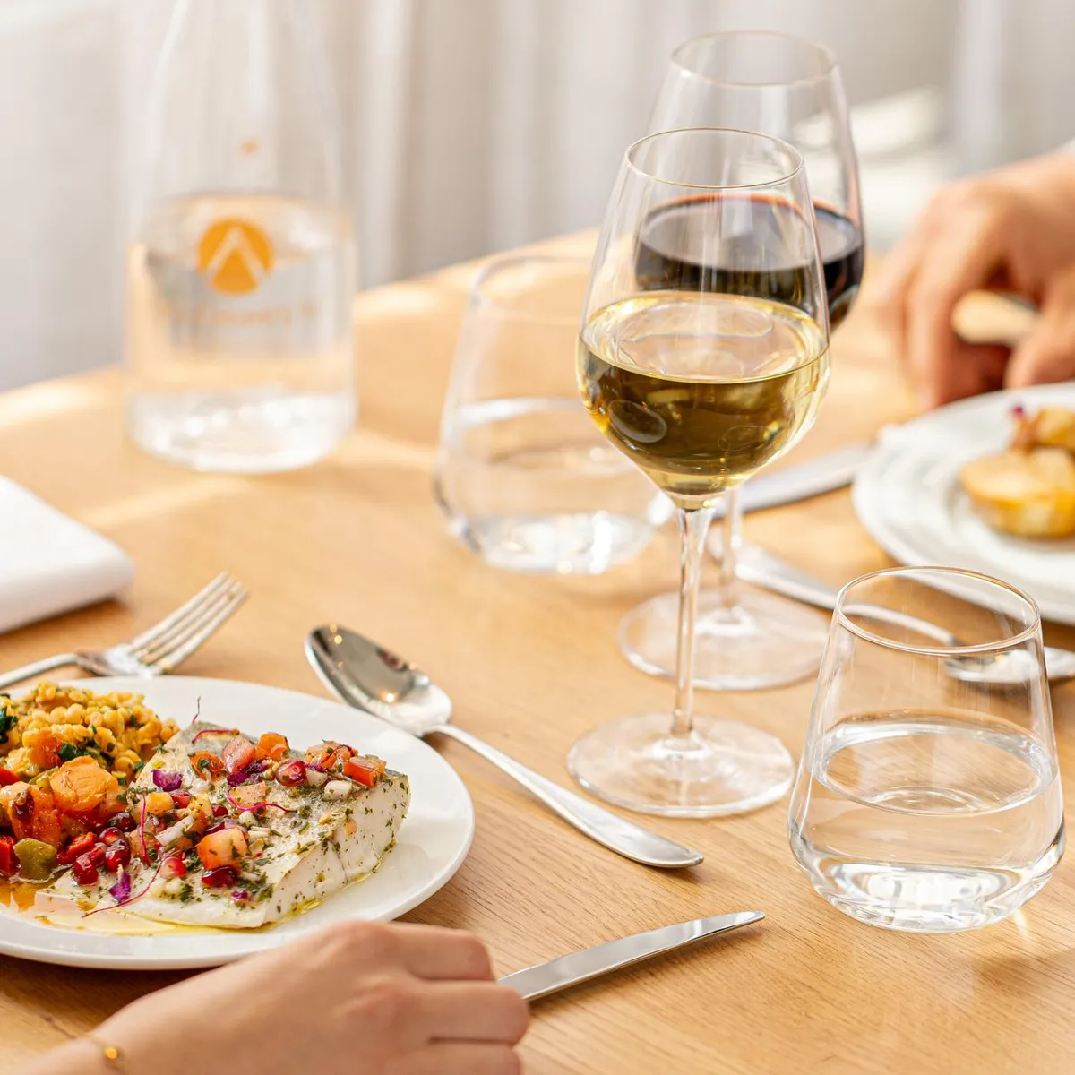 Des personnes sont assises à une table et mangent des plats variés accompagnés de vin et d'eau