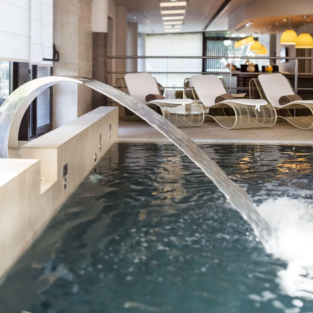 Piscine intérieure avec des chaises longues et un espace de détente en arrière-plan