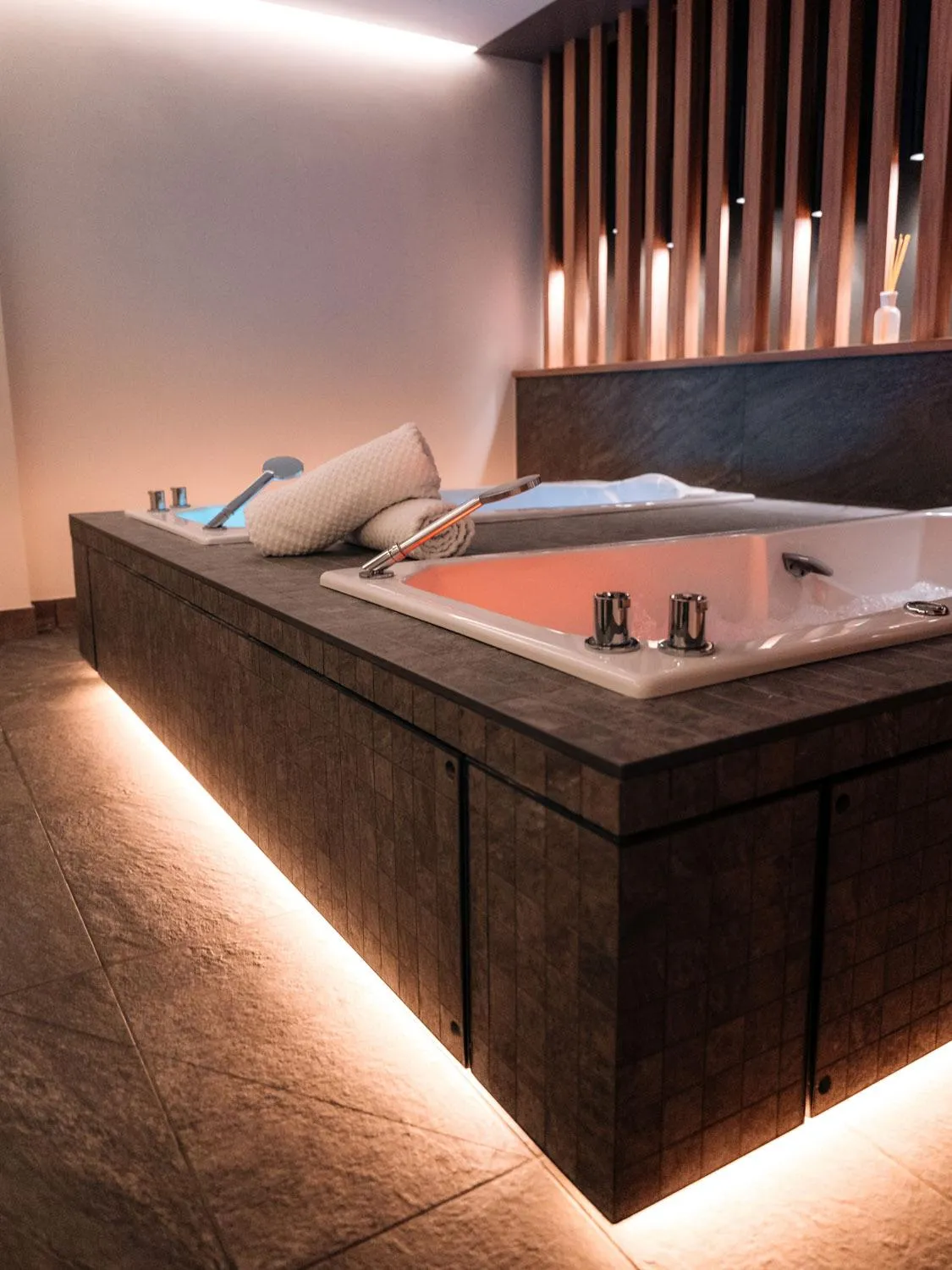 Built-in bathtub with LED lights under the edge, taps, and a towel on the side