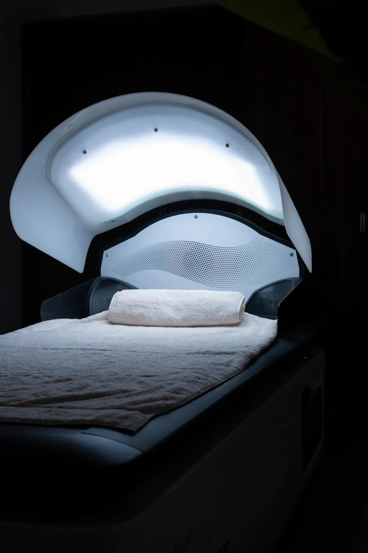 Appareil de luminothérapie avec une lumière blanche allumée et une serviette roulée sur un coussin