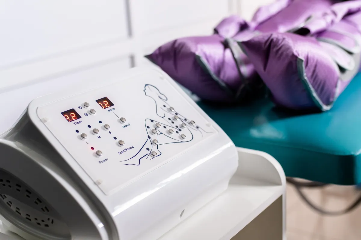 Medizinisches Gerät mit digitalem Bildschirm und Bedientasten, auf einem Tisch mit violettem Kissen im Hintergrund