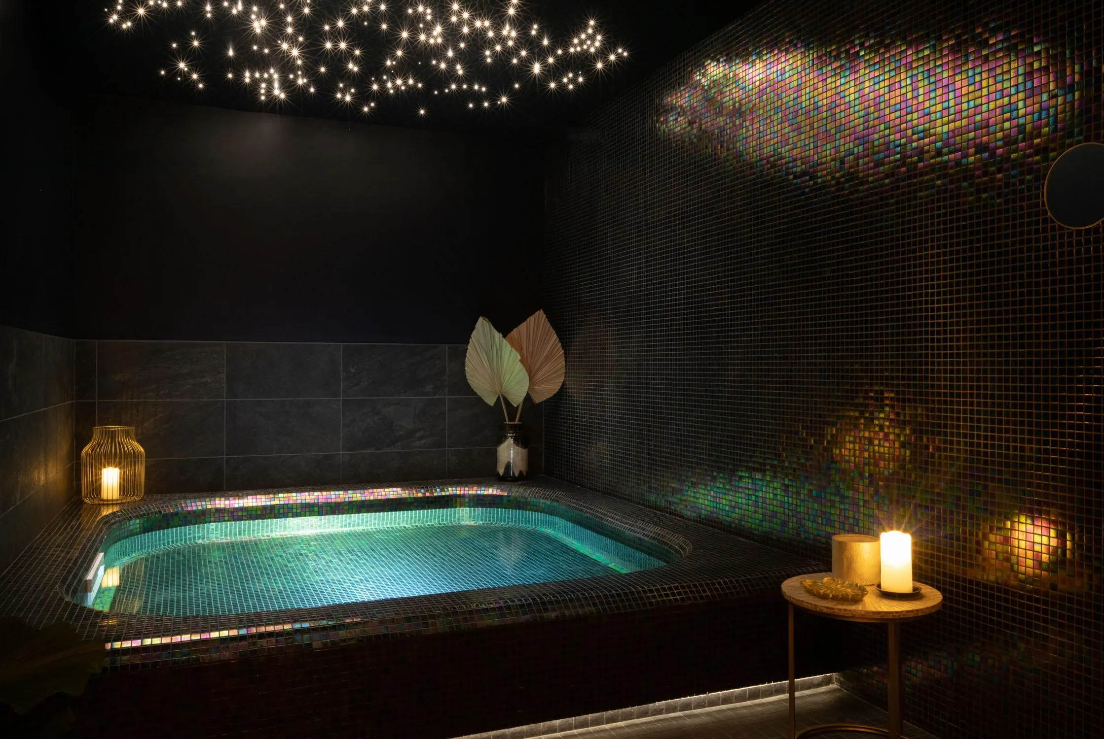Piscine intérieure éclairée avec des mosaïques colorées sur les murs et des étoiles lumineuses au plafond