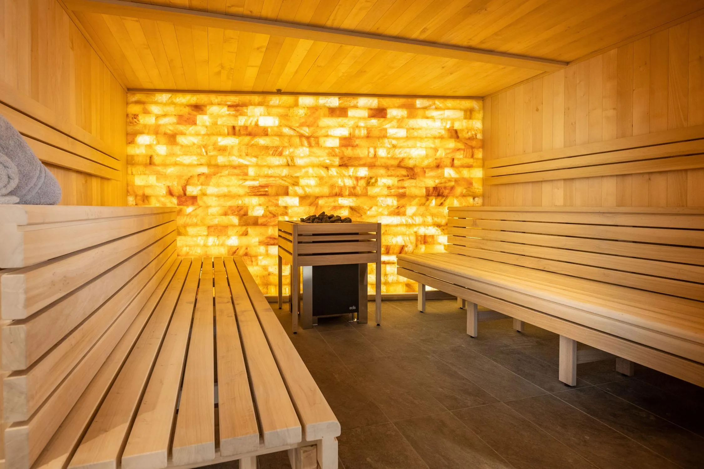 Salle en bois avec des bancs et un mur éclairé par des motifs lumineux