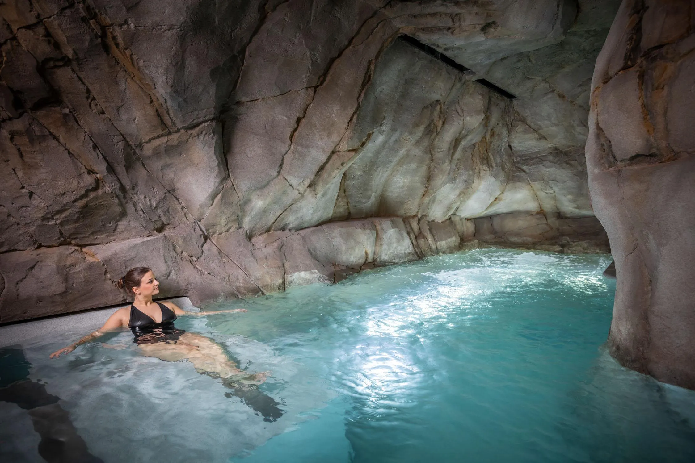 Une personne nage dans une piscine naturelle entourée de rochers