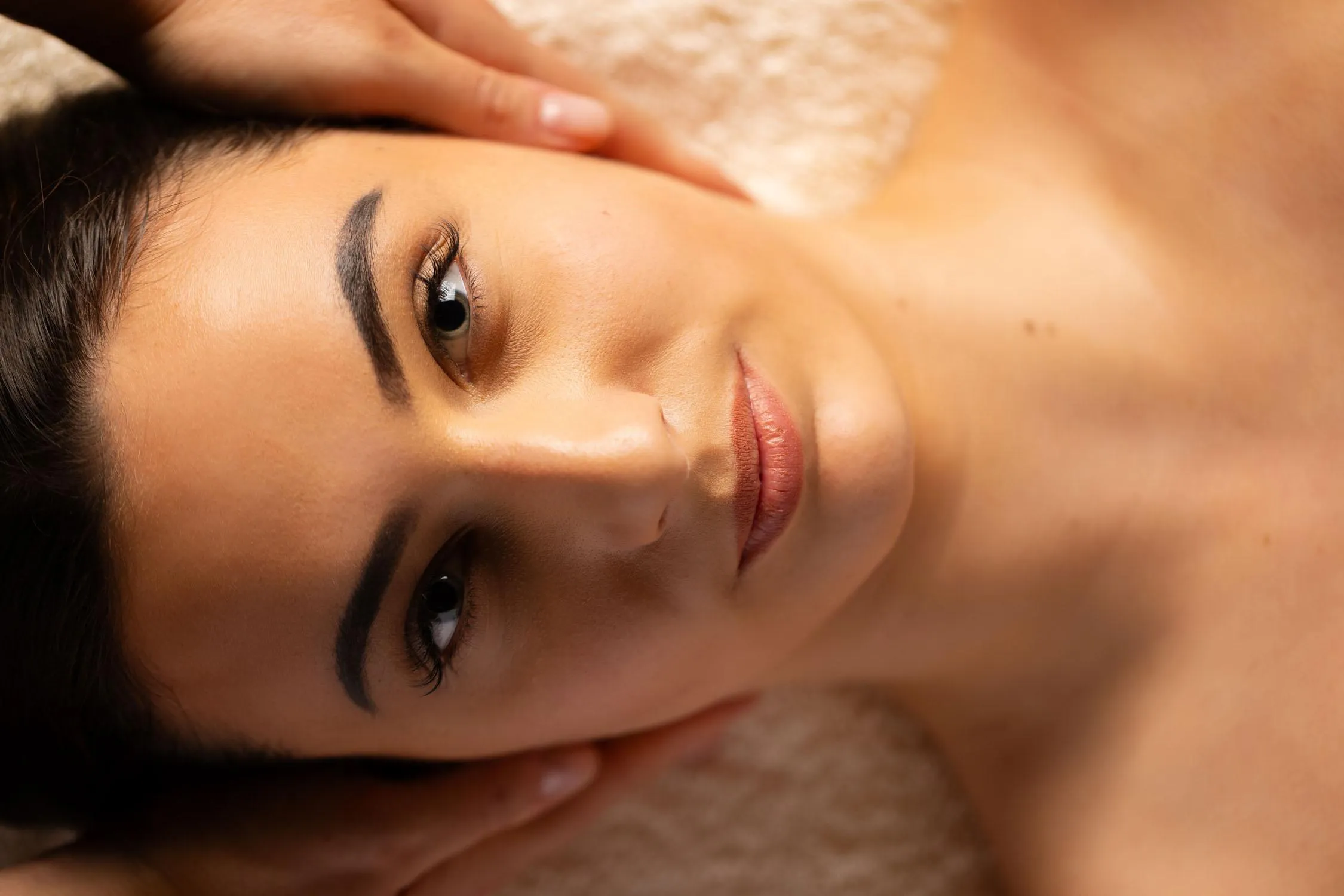Jeune femme allongée avec les yeux ouverts et une main posée sur son visage