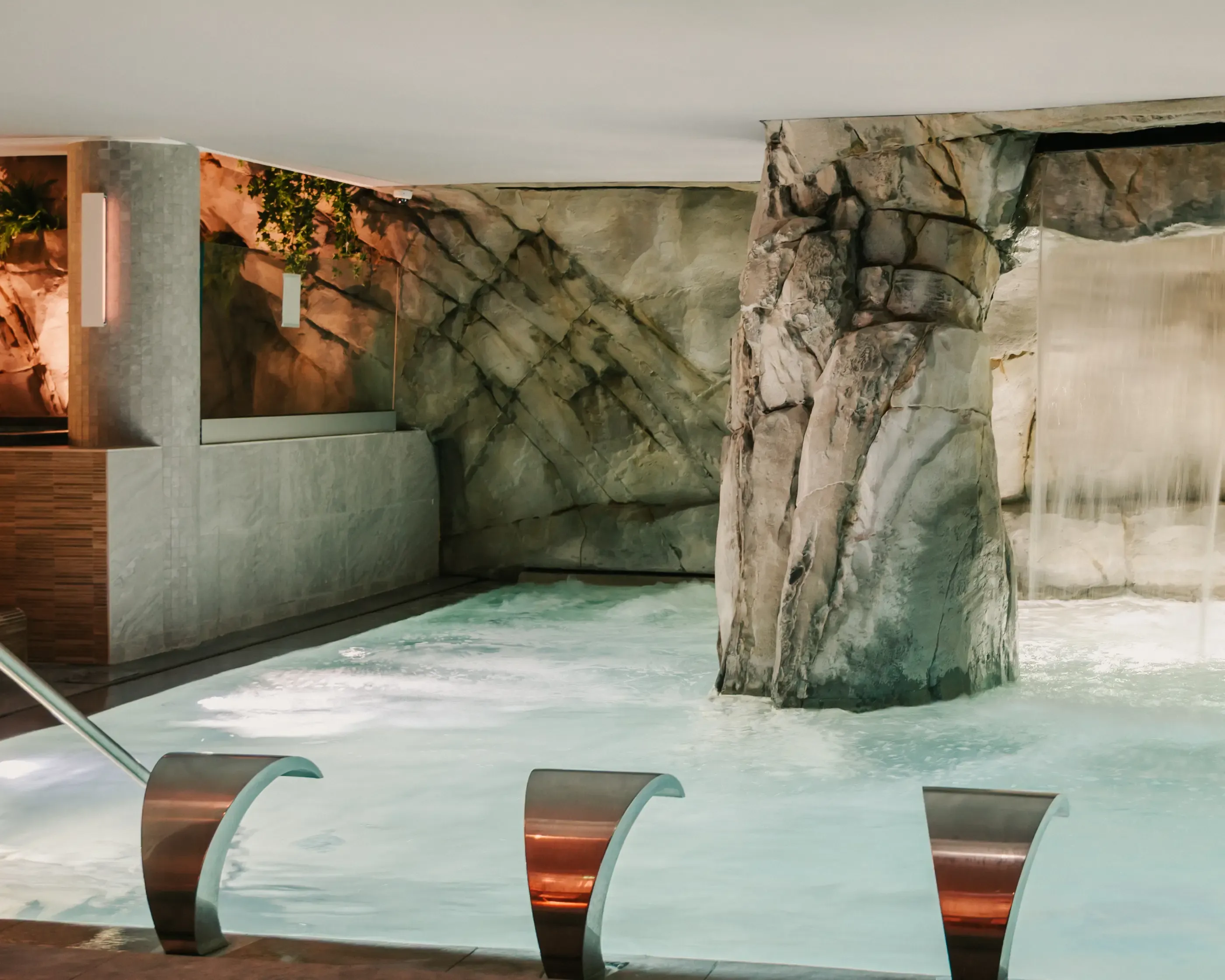 Piscine intérieure avec des rochers artificiels et des bancs métalliques immergés