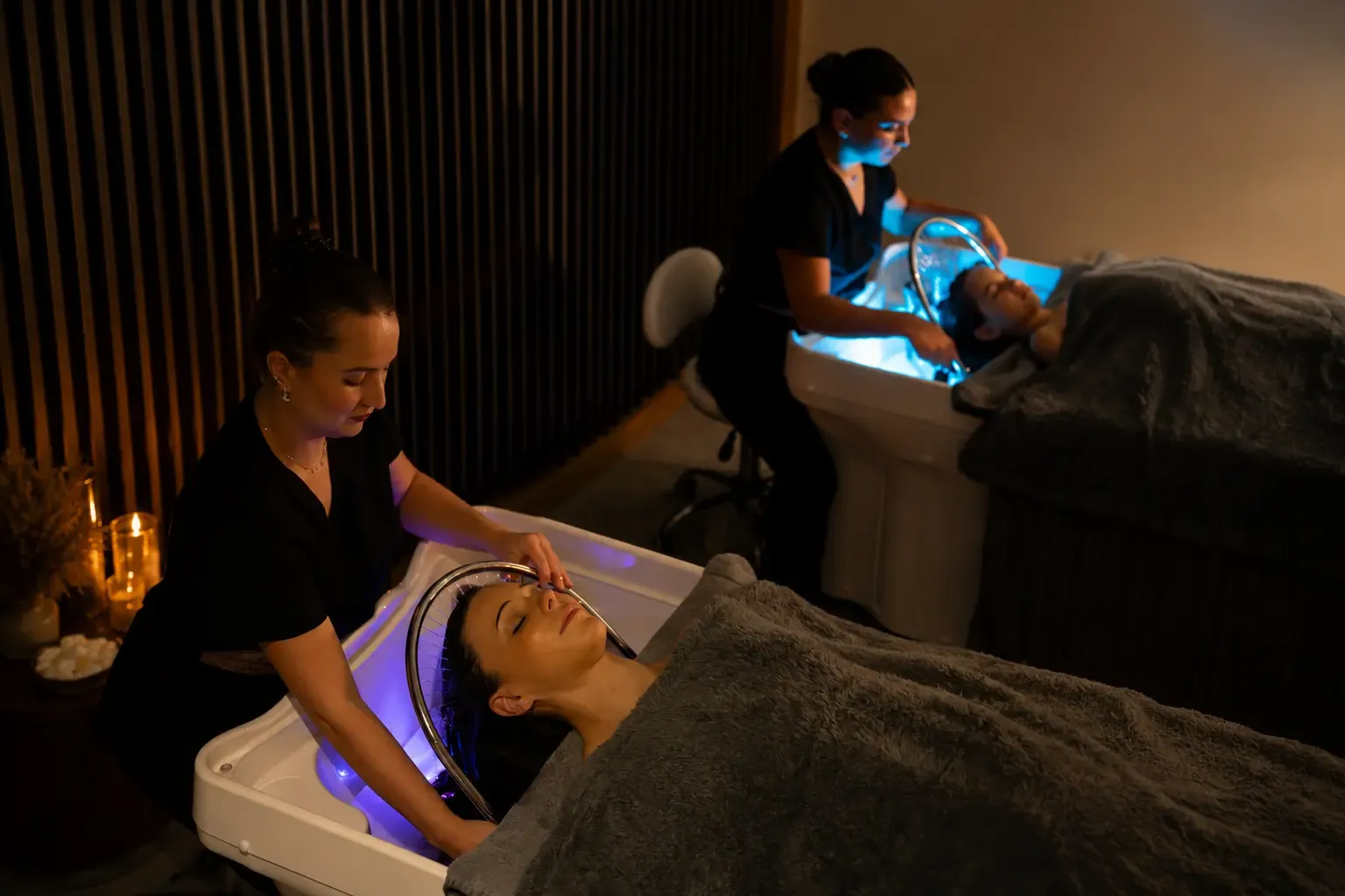 Deux personnes allongées reçoivent un traitement de beauté avec des appareils à lumière bleue dans un salon de soins